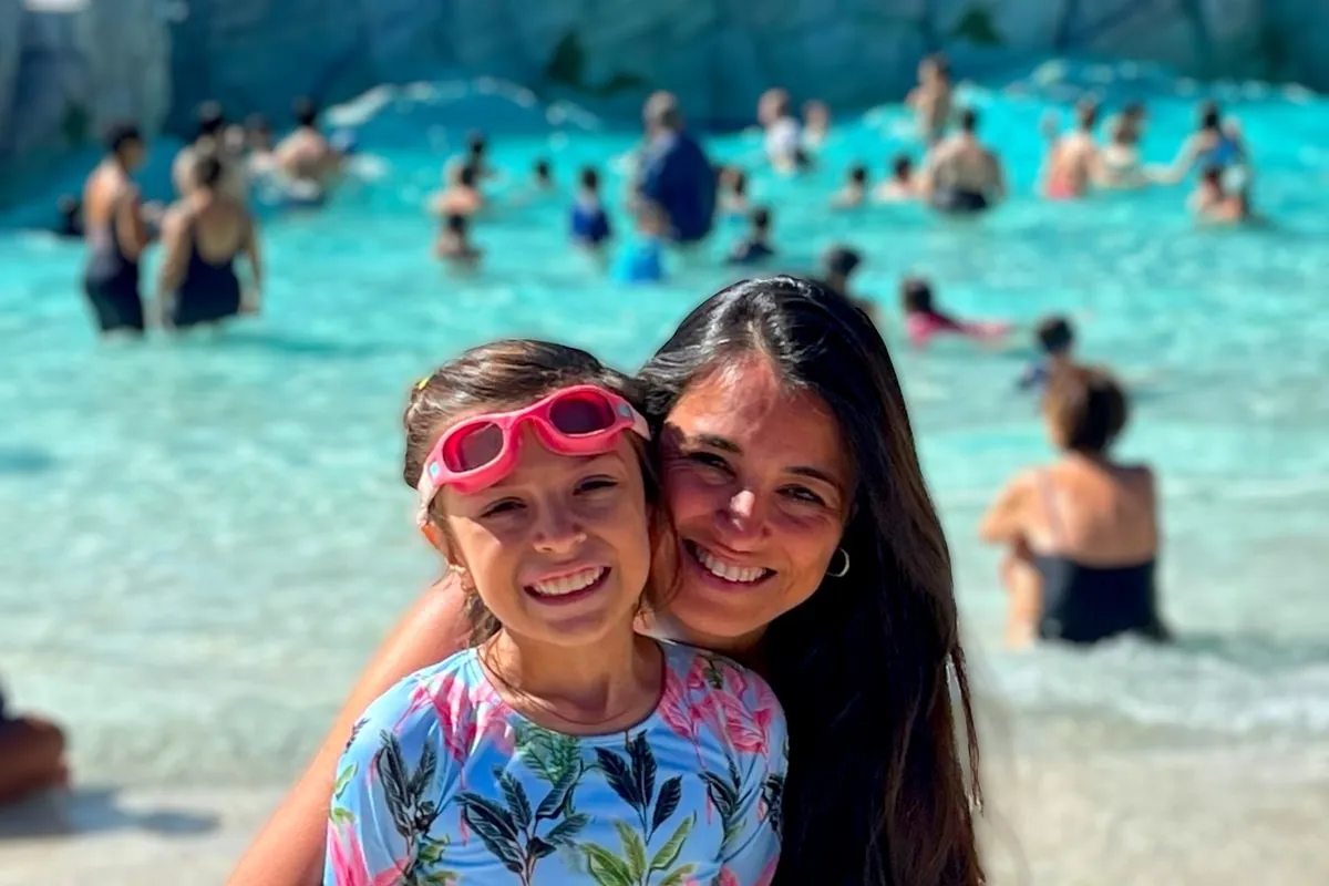 Rafaela, de óculos de natação na testa, abraçada à Michelle numa piscina de ondas