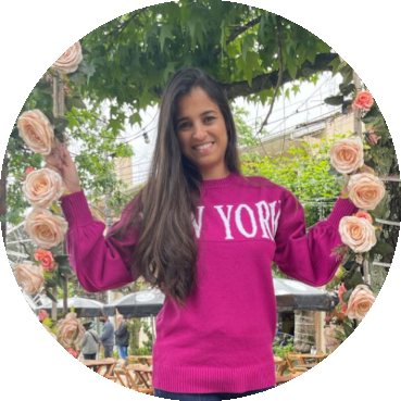 Michelle sorrindo, de blusa rosa, entre flores